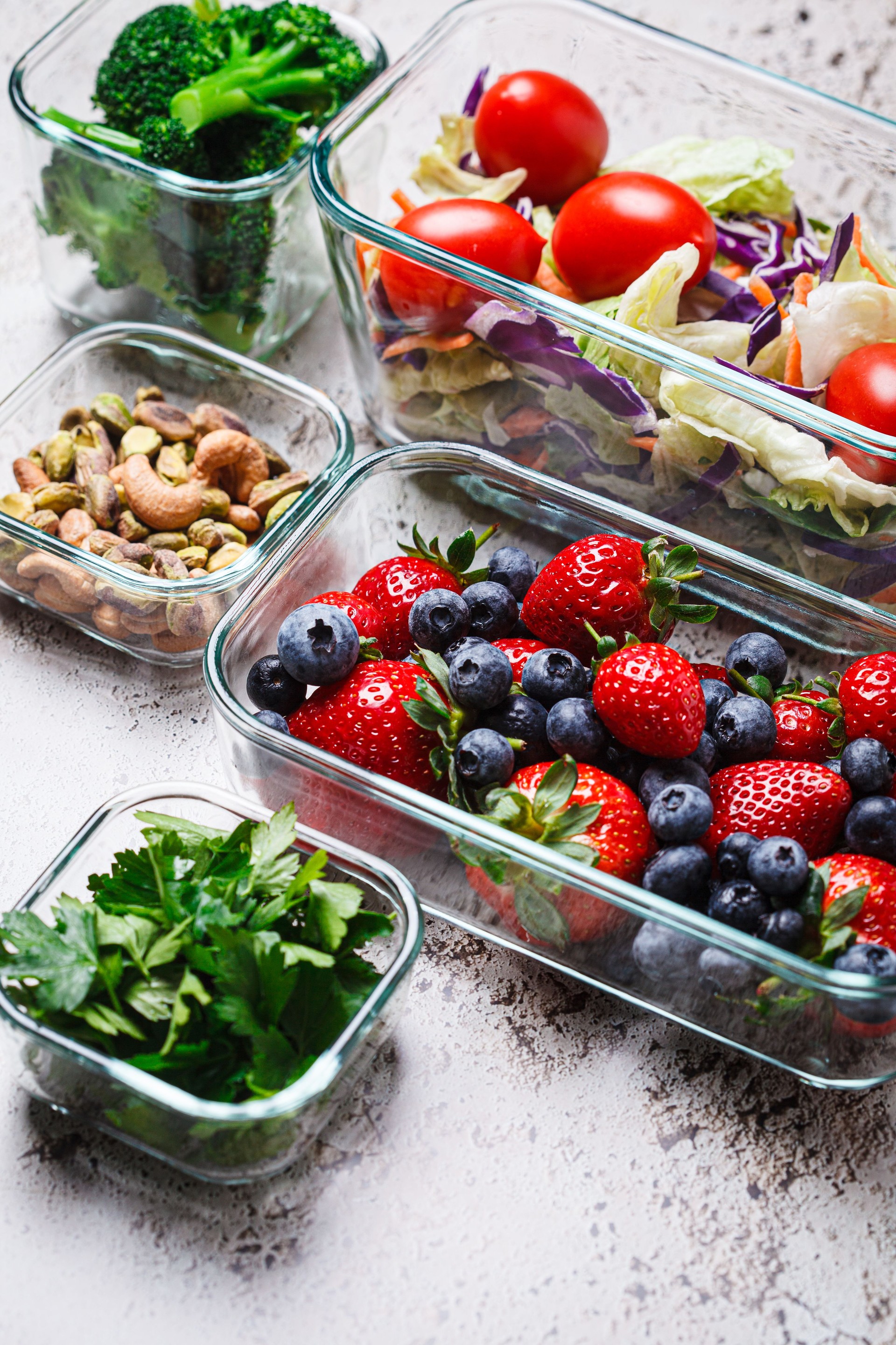 Healthy vegan food preparations for week in glass containers. Vegetables, nuts, berries in boxes.